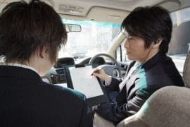 車内で関係者から聞き込みをする探偵