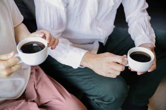 隣同士でコーヒーを飲む不倫カップル